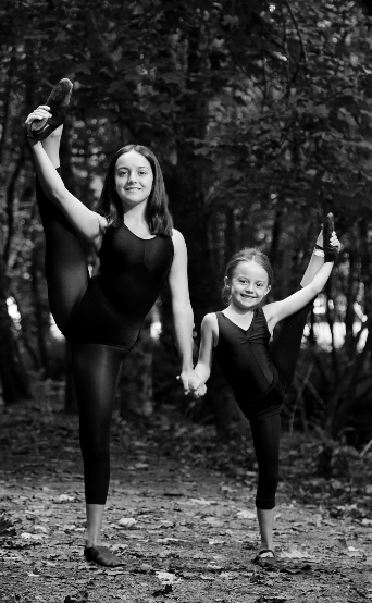 Sisters holding one leg up in ballet pose
