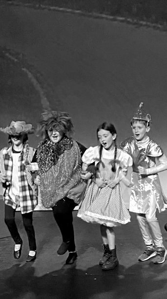 Kids dressed from the Wizard of Oz singing on stage